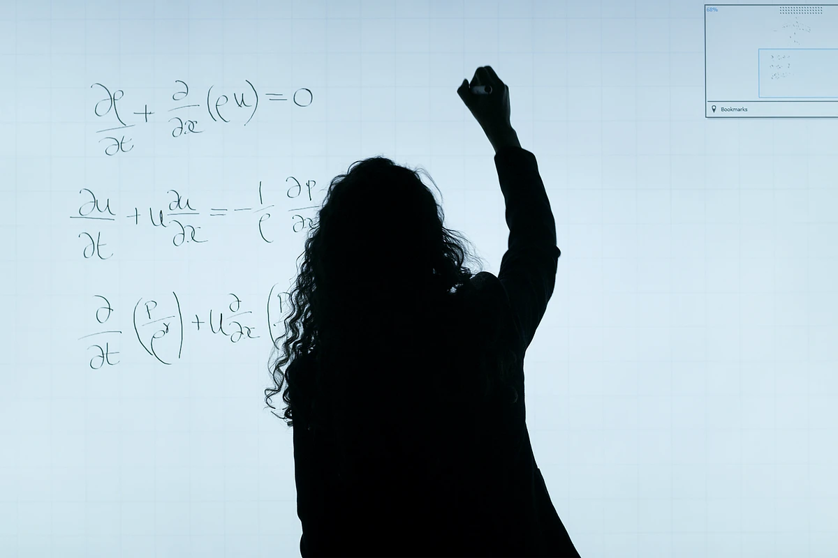 Silhouette of student writing formulas on whiteboard